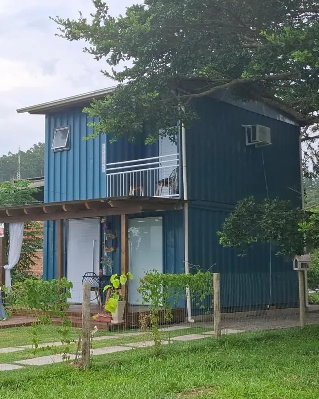 A Casa Container vista de lado, com o jardim e a figueira atrás