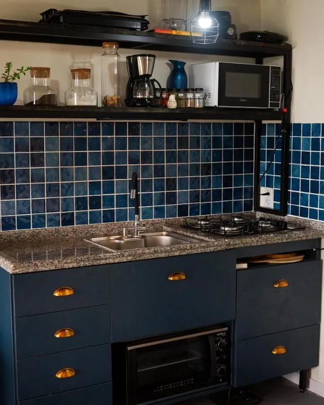A cozinha com armários azuis, pia, fogão e micro-ondas