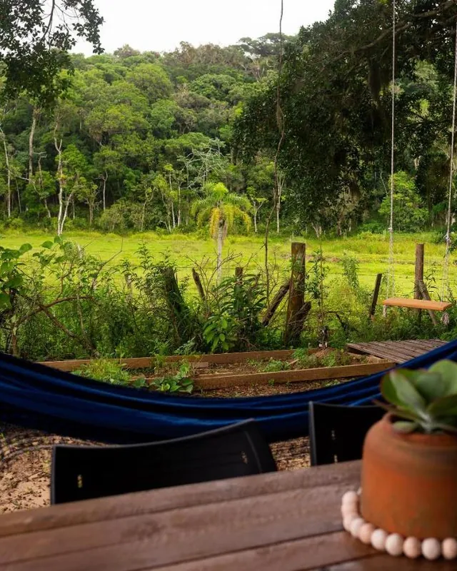 Uma rede azul na varanda, de frente para o verde da mata